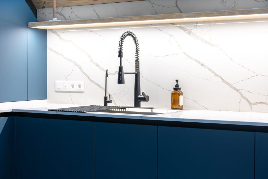 Large format white marble backsplash with grey veining and under-cabinet lighting.