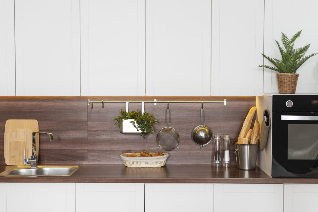 Warm wood-texture backsplash panels with a gold hanging utensil rail.